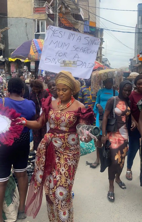 Single mom storms market with placard to search for single Dad to marry (Watch Video)